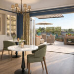Artist's impression of a room with bistro tables and doors open onto a sunny terrace at Elland Court Care Home, Leeds