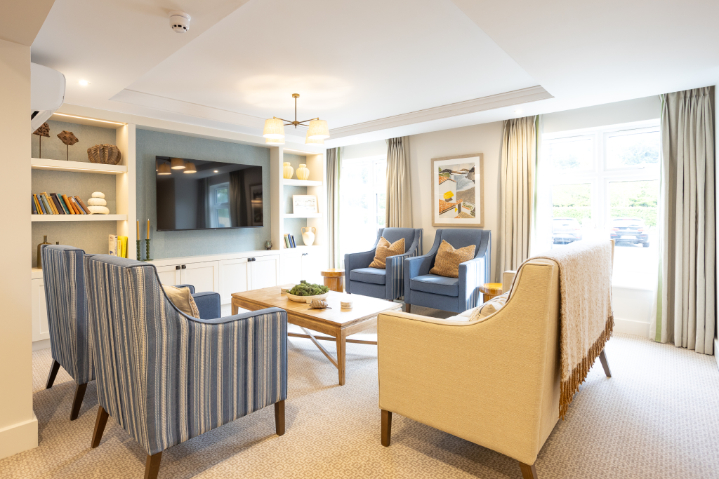 Lounge with striped armchairs, cream sofa and large windows at The Maltings Care Home, Bridlington