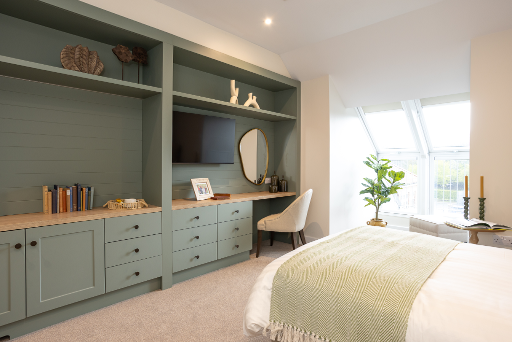 Bedroom with sage green fitted shelving, wall-mounted TV and desk at The Maltings Care Home, Bridlington