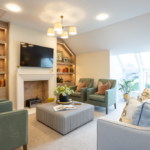 Lounge with fireplace, lit bookshelves and green armchairs at The Maltings Care Home, Bridlington
