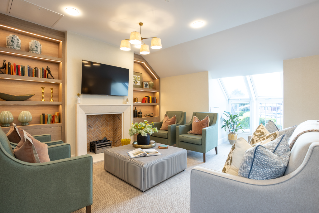 Lounge with fireplace, lit bookshelves and green armchairs at The Maltings Care Home, Bridlington