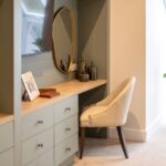 Dressing table with a gold oval mirror and sage-green drawers in a bedroom at The Maltings Care Home, Bridlington