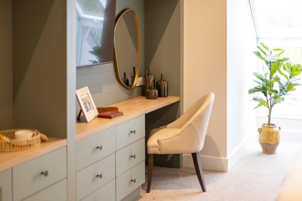 Dressing table with a gold oval mirror and sage-green drawers in a bedroom at The Maltings Care Home, Bridlington