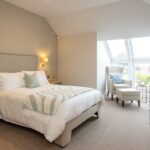 Bedroom with double bed, wall lights and an armchair by a large window at The Maltings Care Home, Bridlington