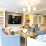 Lounge with blue armchairs, coffee table and wall-mounted TV in fitted shelving at The Maltings Care Home, Bridlington