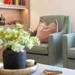 Sage-green armchairs with pink cushions beside a vase of wild flowers in a lounge at The Maltings Care Home, Bridlington
