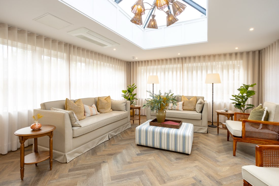 Light-filled orangery with sofas, cane armchairs and a glass roof lantern at The Maltings Care Home, Bridlington