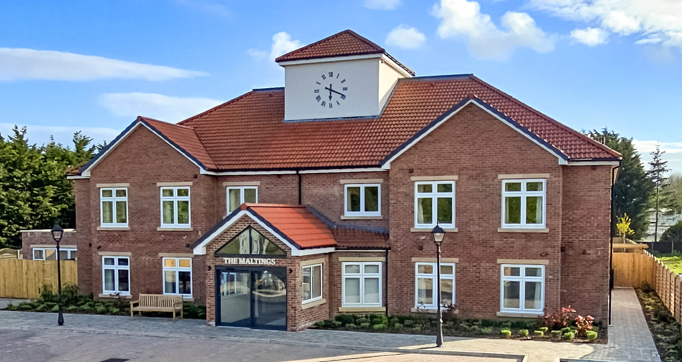 Red-brick front with clock tower and glazed entrance porch at The Maltings Care Home, Bridlington