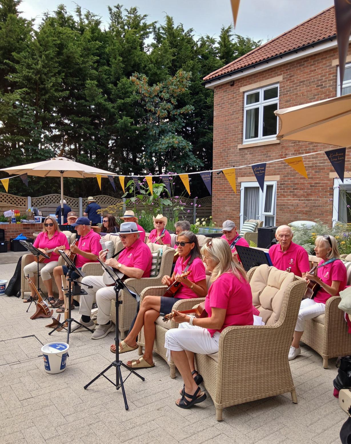 Ukulele band in pink polo shirts playing in the courtyard garden at The Maltings Care Home, Bridlington