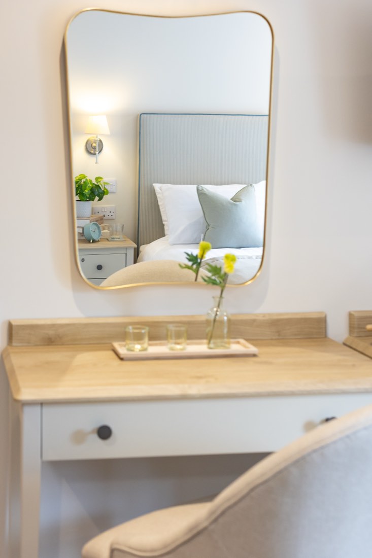 Dressing table with a gold-framed mirror reflecting a made bed in a bedroom at The Maltings Care Home, Bridlington Dressing table with a gold-framed mirror reflecting a made bed in a bedroom at The Maltings Care Home, Bridlington