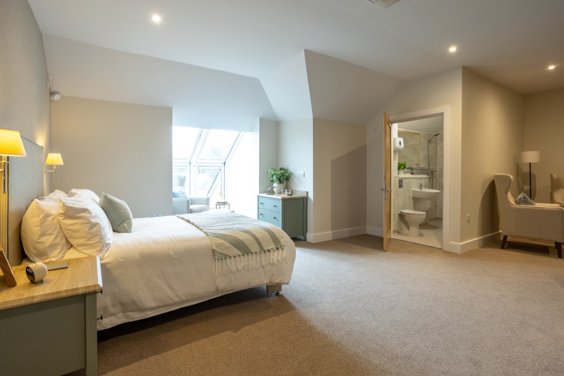 Large bedroom with a tall glazed window and the door open to the en-suite shower room at The Maltings Care Home, Bridlington Large bedroom with a tall glazed window and the door open to the en-suite shower room at The Maltings Care Home, Bridlington