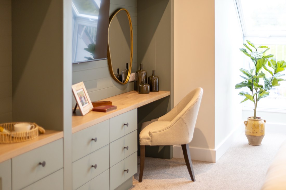 Dressing table with a gold oval mirror and sage-green drawers in a bedroom at The Maltings Care Home, Bridlington