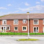 Wide view of the two-storey red-brick front and railed front lawn at Whitby Court Care Home, Whitby