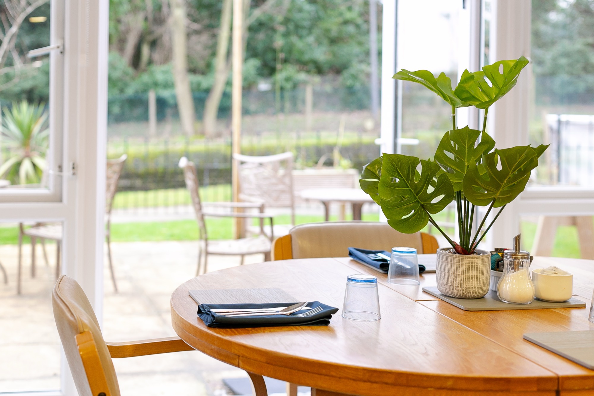 Dining table set for a meal beside doors to the garden patio at Whitby Court Care Home, Whitby