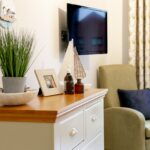 Bedroom with chest of drawers, armchair and wall-mounted TV at Whitby Court Care Home, Whitby