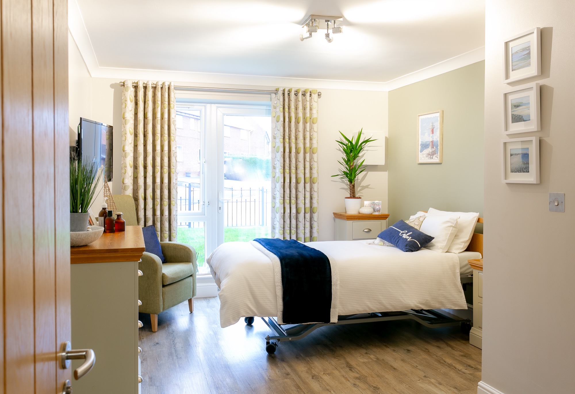 Bright bedroom with patio doors, armchair and single bed at Whitby Court Care Home, Whitby