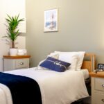 Neatly made bed with cushion and bedside table at Whitby Court Care Home, Whitby
