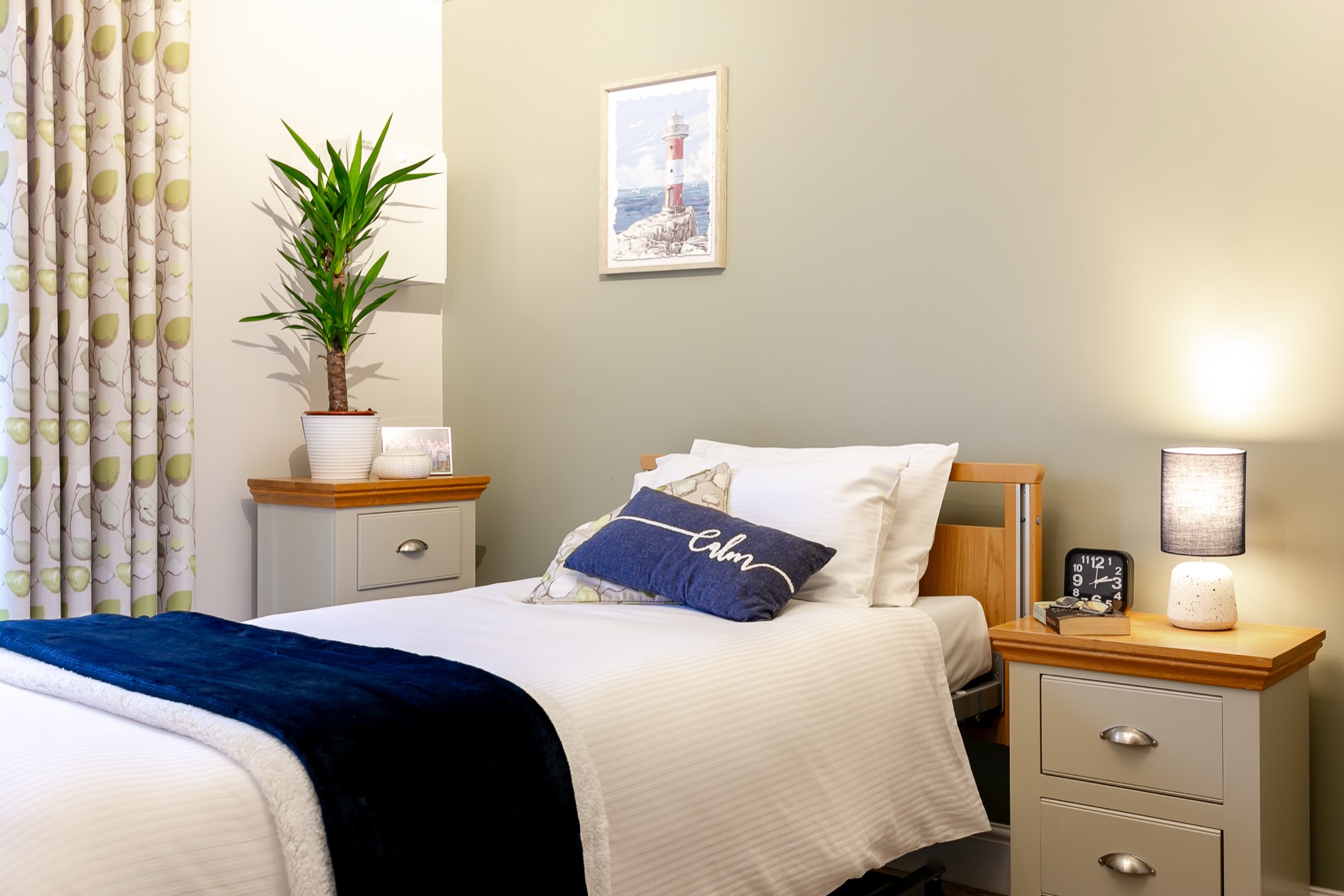 Neatly made bed with cushion and bedside table at Whitby Court Care Home, Whitby