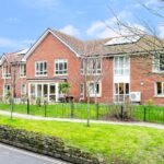 Two-storey red-brick exterior with railed front lawns and patio seating at Whitby Court Care Home, Whitby